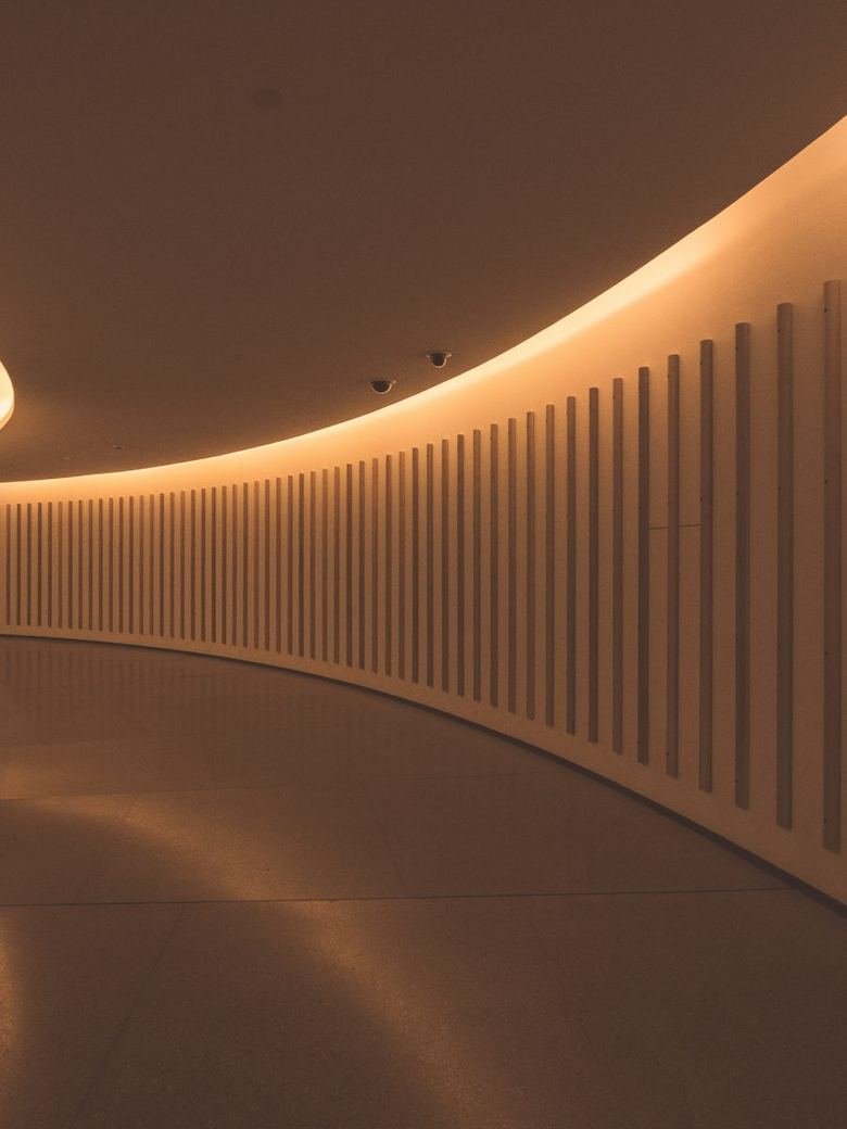 Curved corridor lit by concealed cove lighting